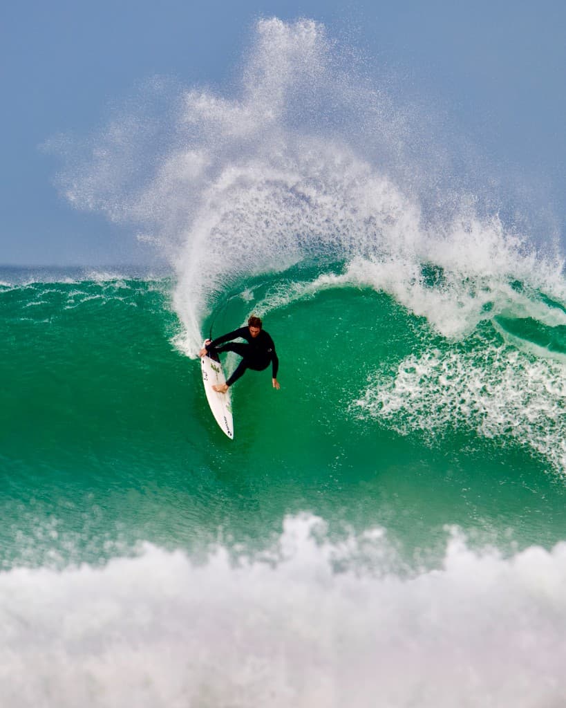 Surfer turning on a large green wave with spray